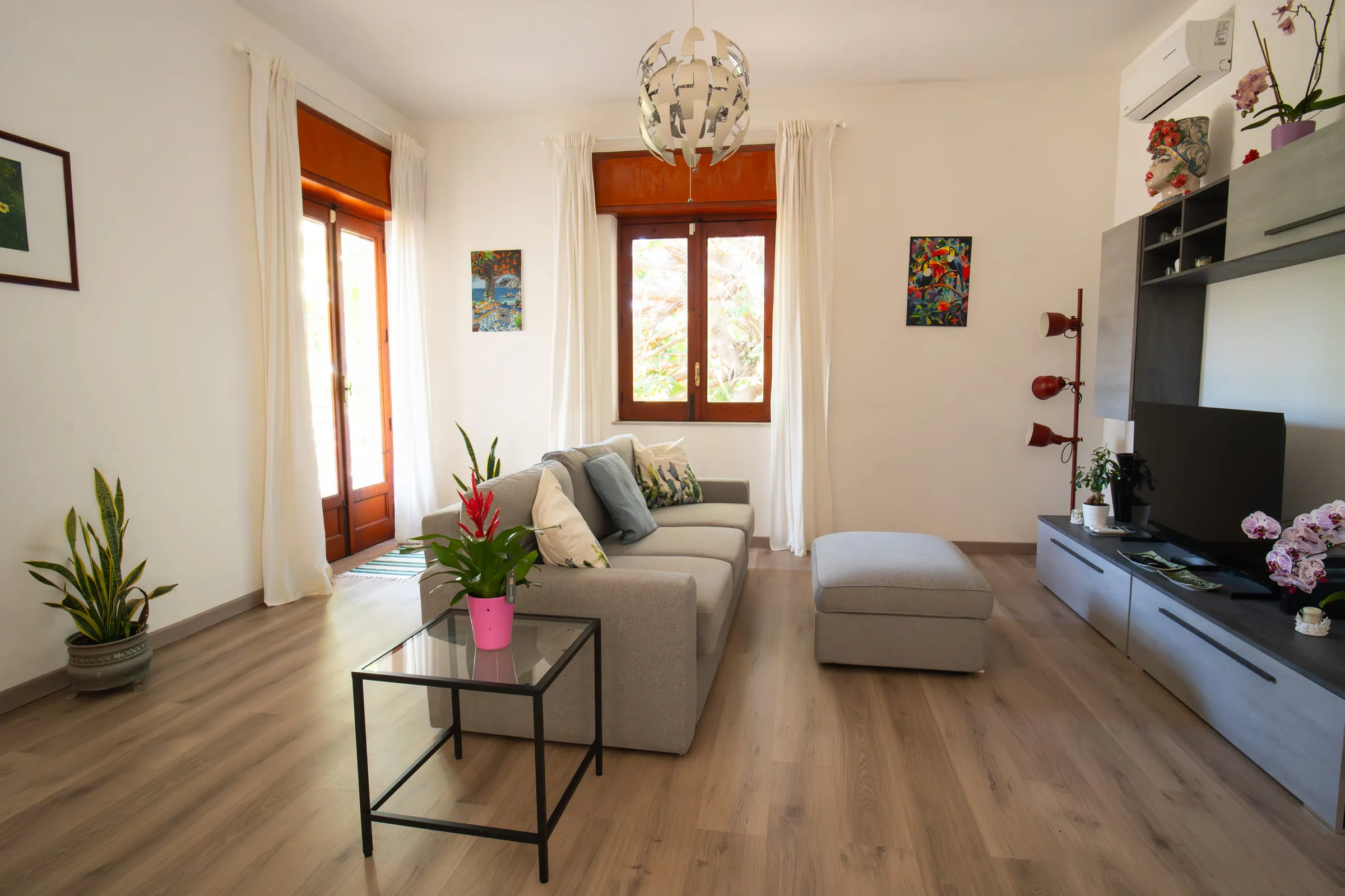 The living room with the grey sofa, glass coffee table and French door onto the balcony.