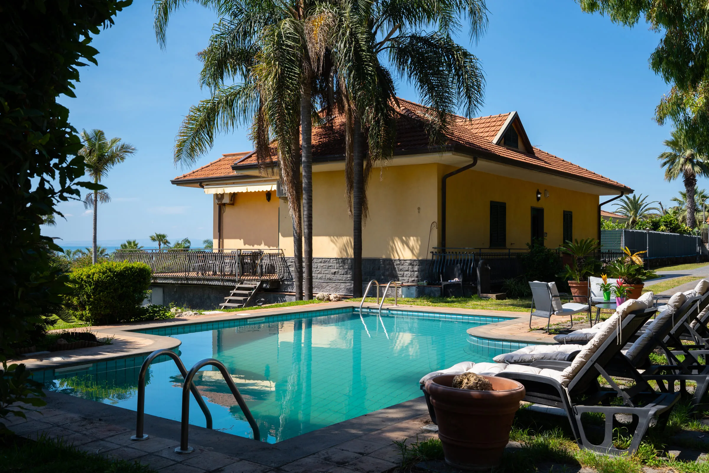 The villa seen from the poolside, sun loungers laid out on the terrace.