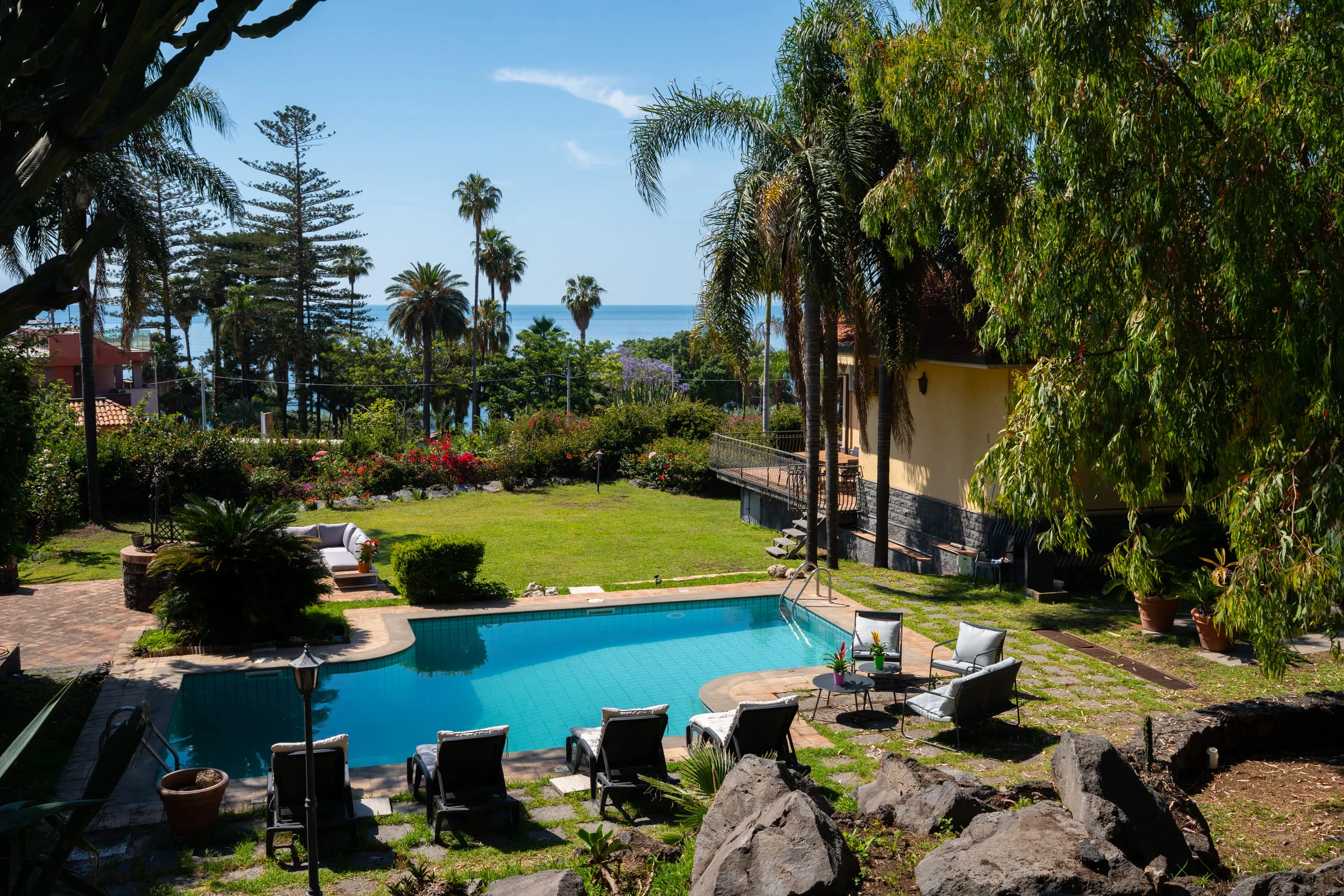 The pool edged in lava rock, with the garden and the sea behind.