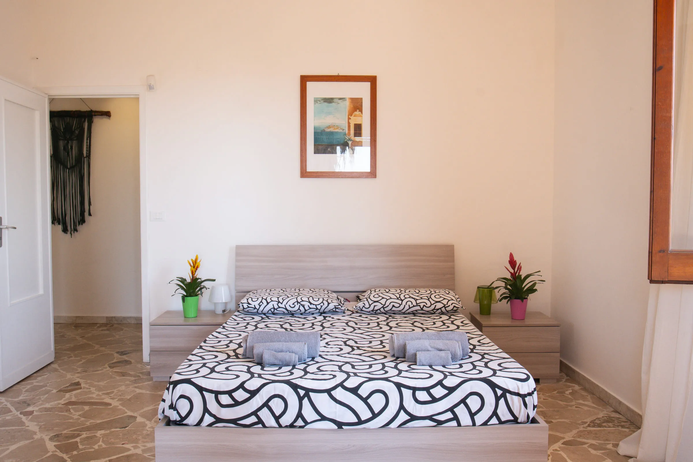 Double bedroom with a stone floor and a painting above the bed.