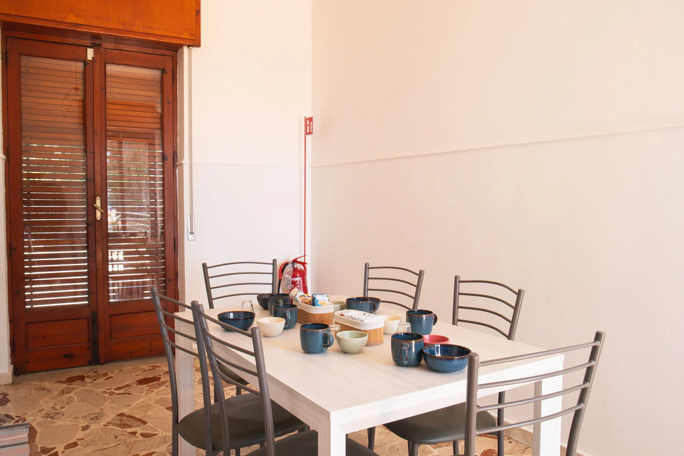 The kitchen table laid, beside the louvred door.