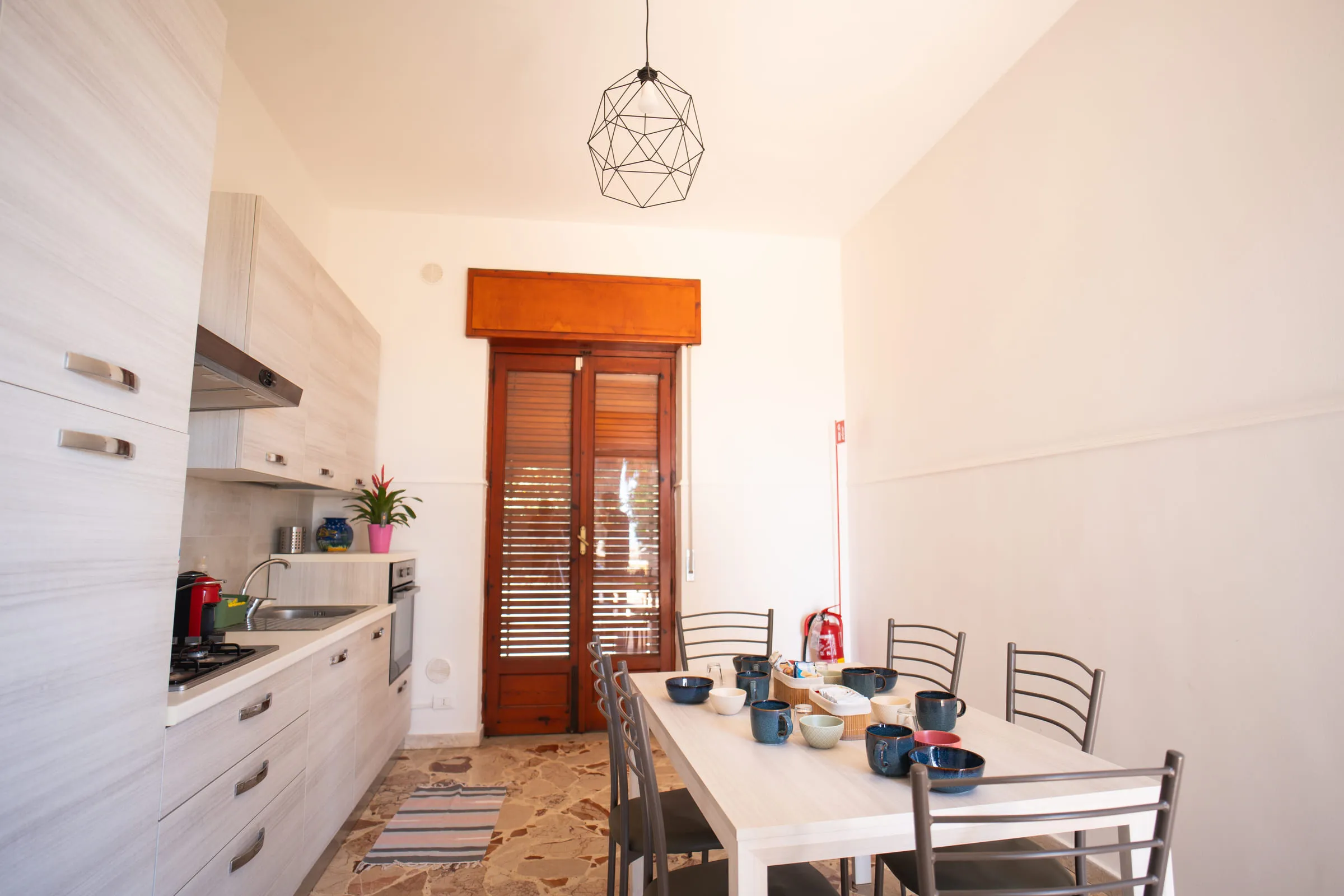The galley kitchen with the dining table and the louvred door.