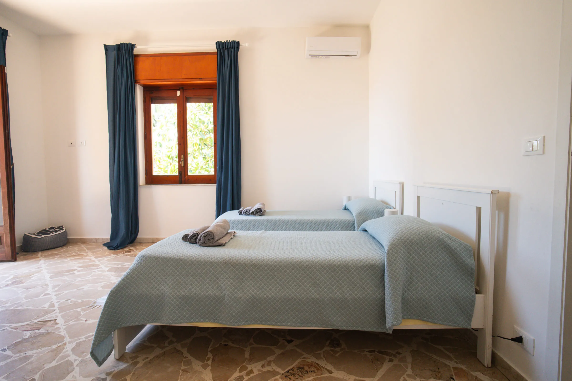 Bedroom with two single beds pushed together and blue curtains.