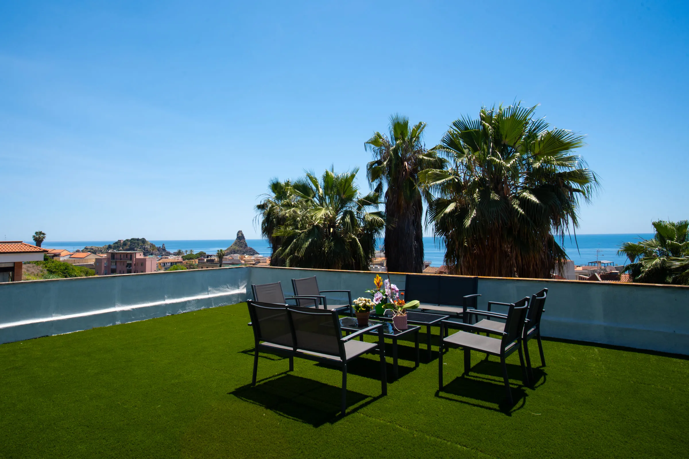 The roof terrace with outdoor seating and the faraglioni on the horizon.