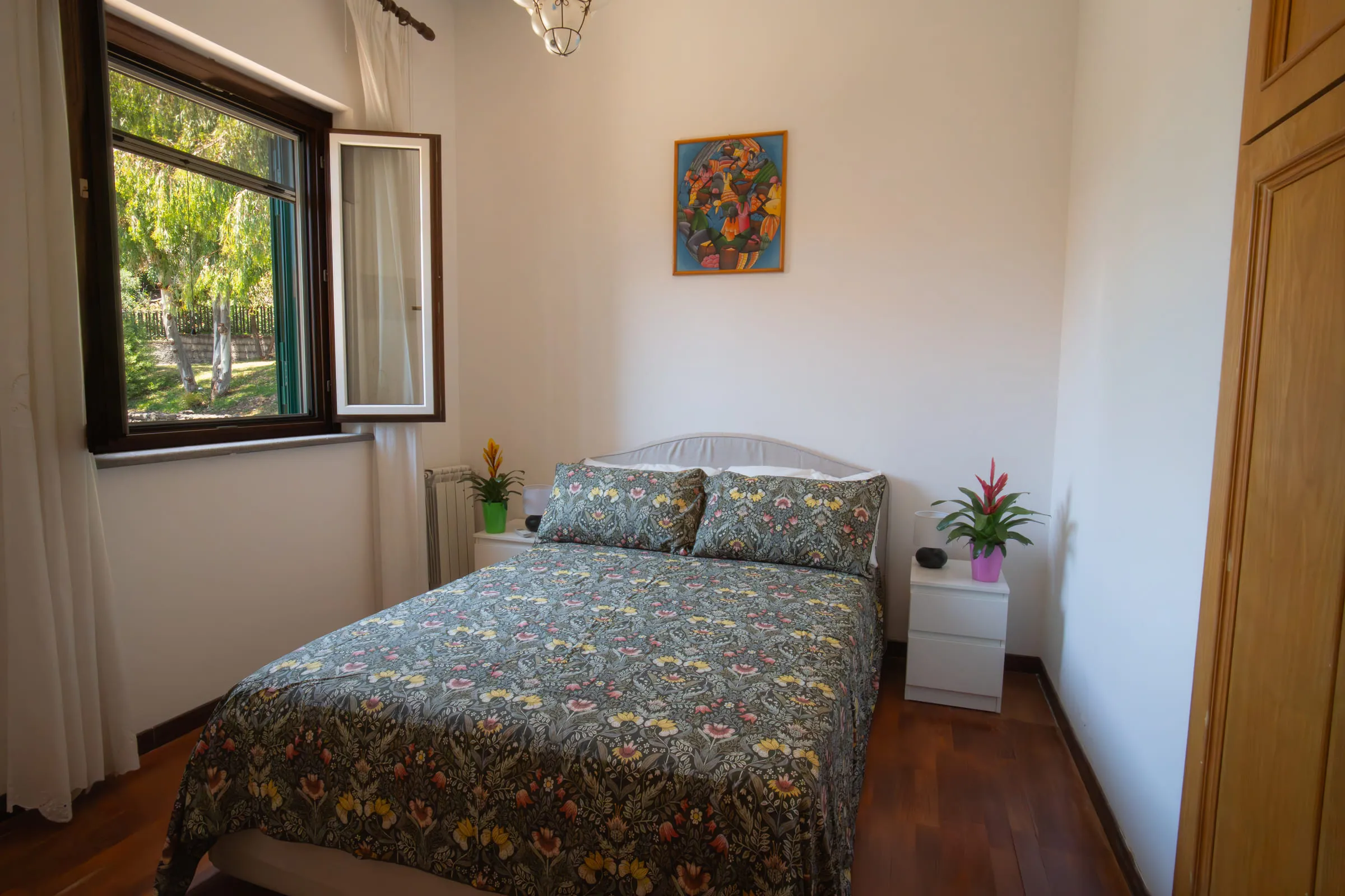 Double bedroom with parquet floor and a window onto the greenery.