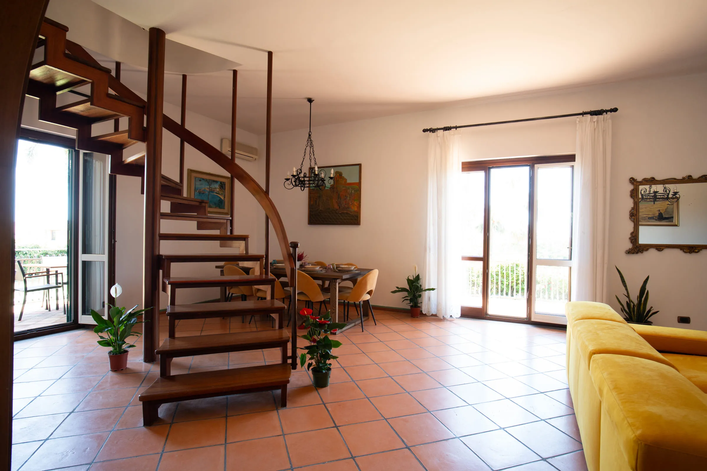 The living room with the wooden spiral staircase, the dining area and French windows.