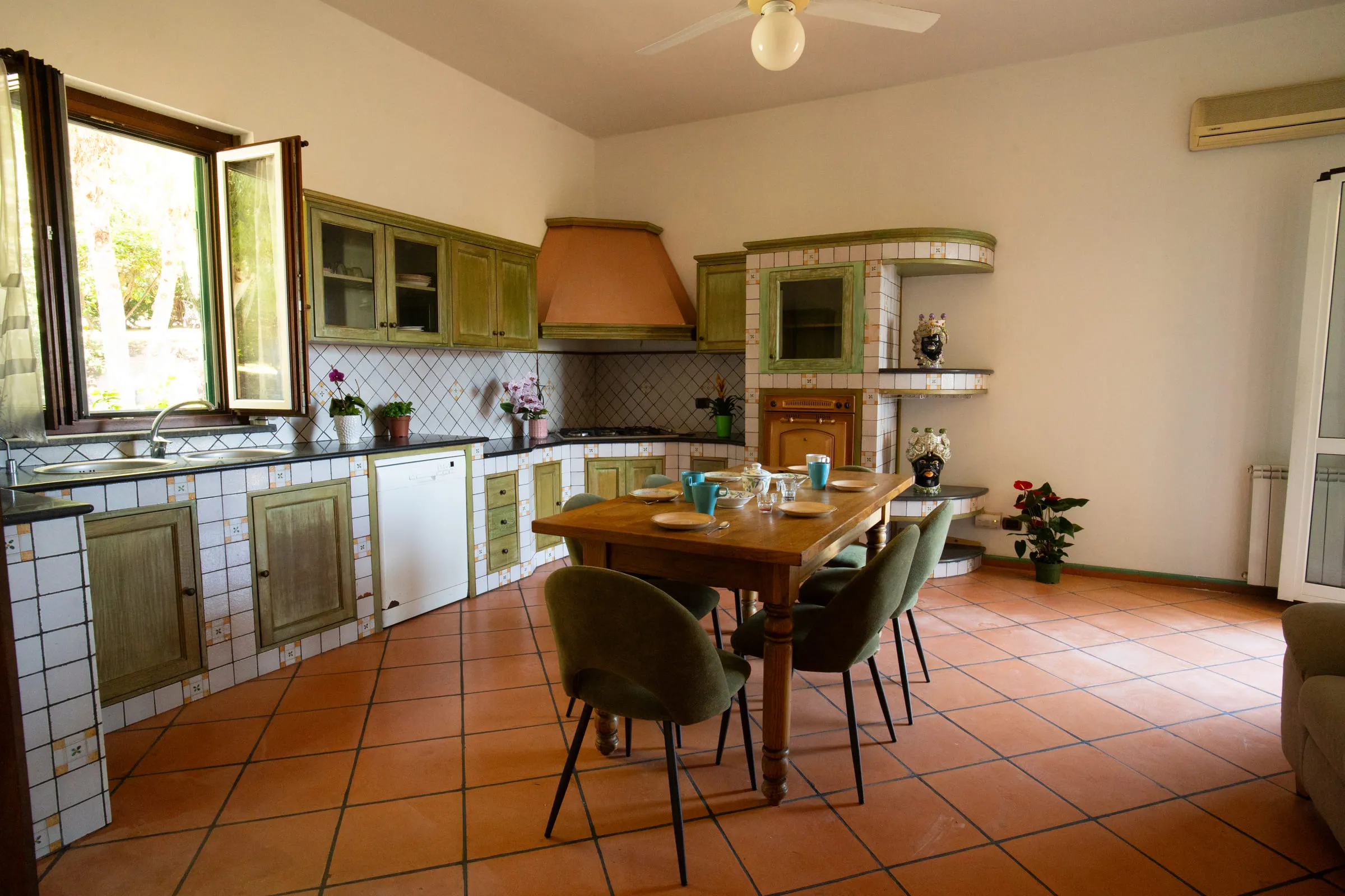 The green fitted kitchen with the wooden dining table.