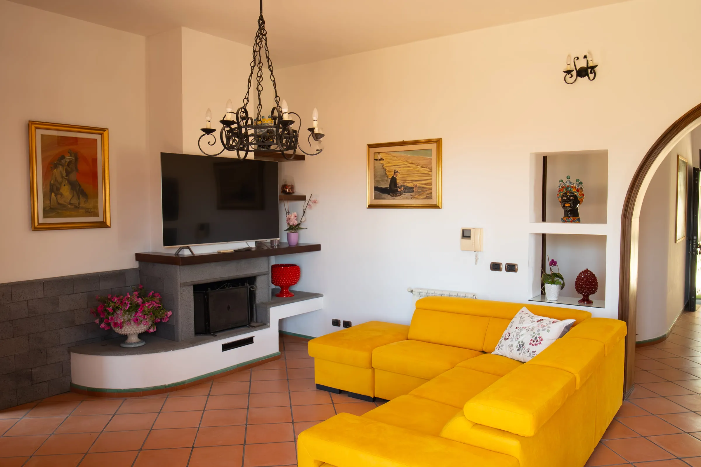 Sitting area with a masonry fireplace, television and yellow sofa.