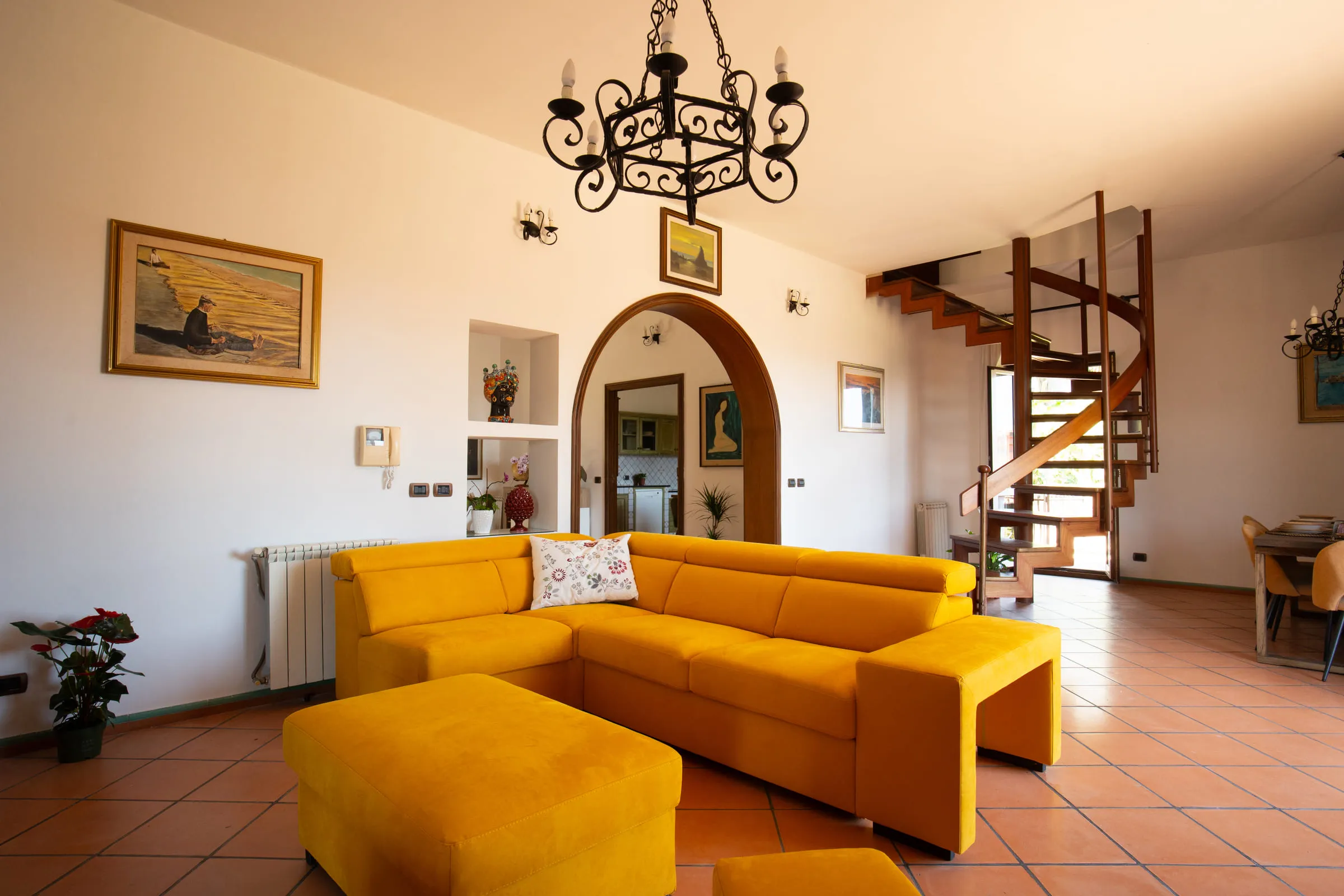 The living room with the yellow sofa, the spiral staircase and the fireplace.