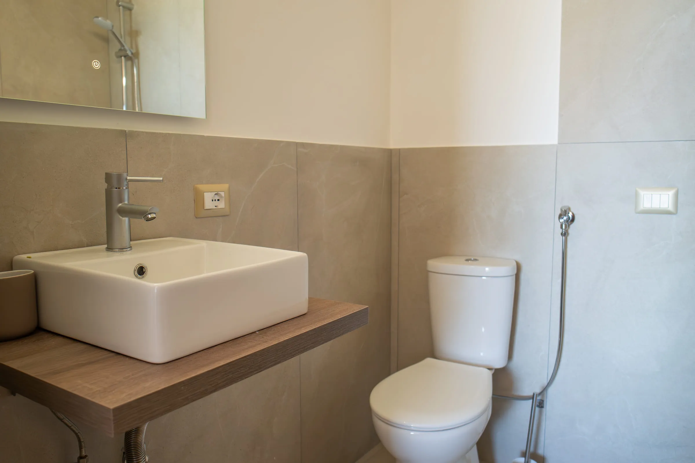 Modern bathroom with a square basin and grey tiles.