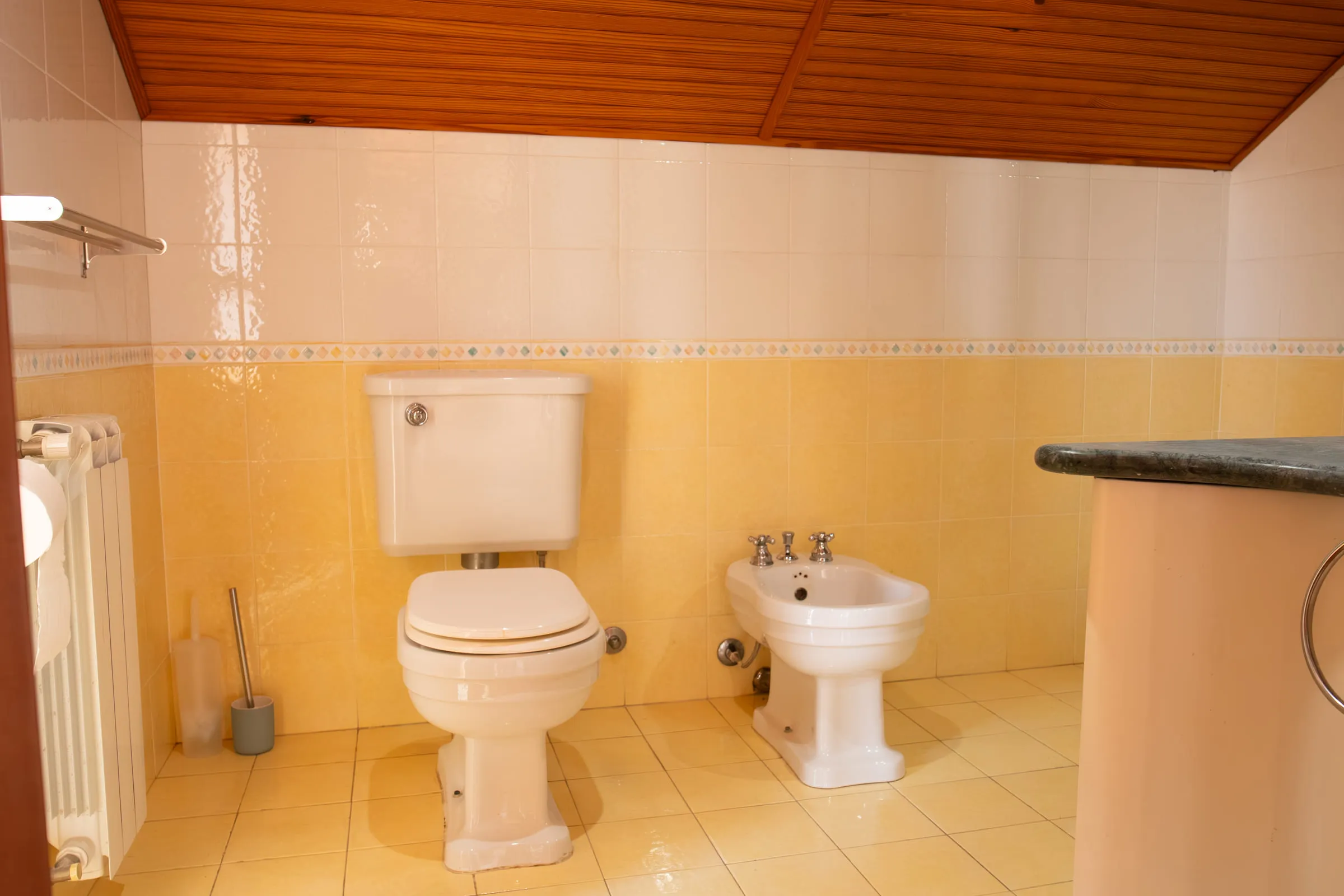 Bathroom with yellow tiles and a timber ceiling.