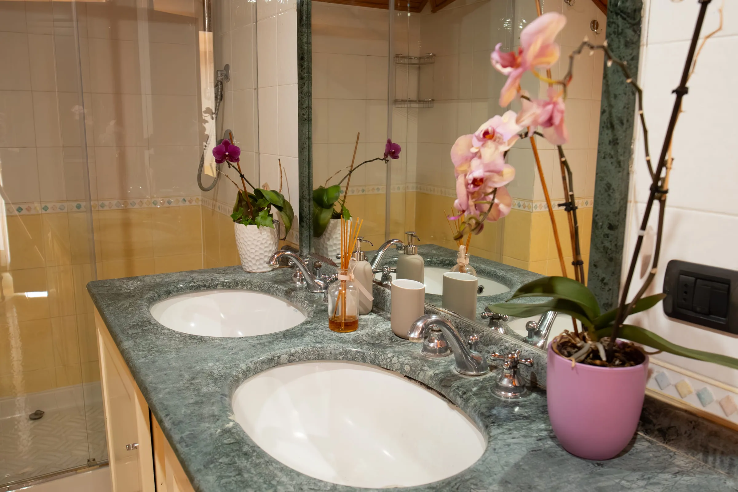 Bathroom with a double basin in green marble and a mirror.