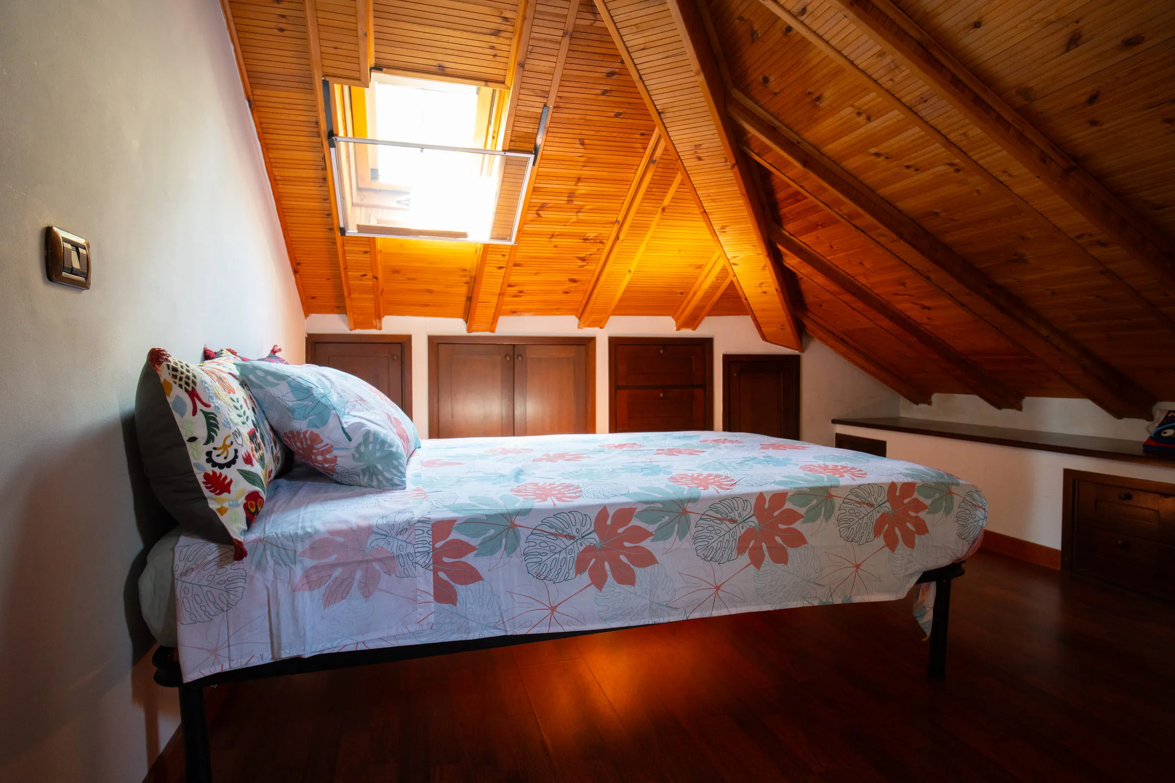 Attic bedroom with a three-quarter bed, a skylight and a timber ceiling.